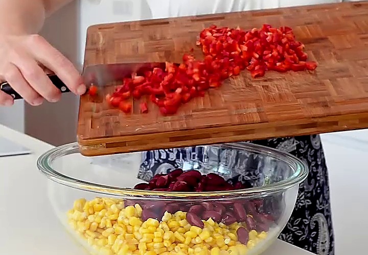 Nakrájená červená paprika přidaná ke kukuřici a fazolím