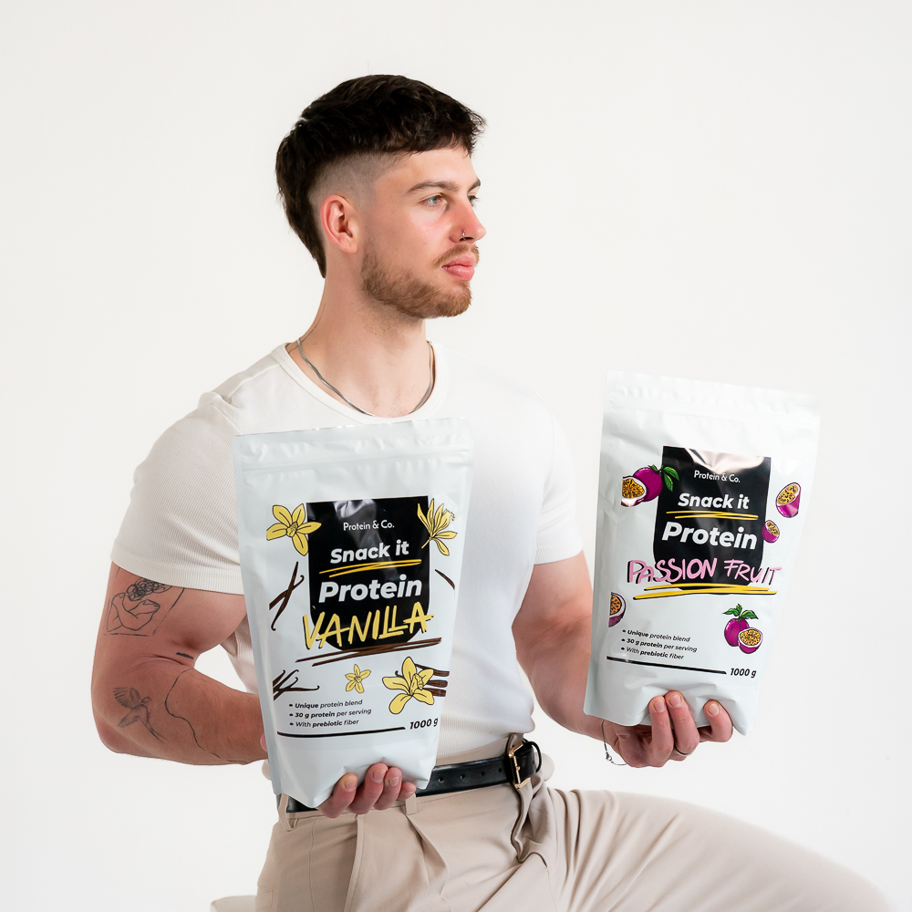 Muž drží dve balenia Snack it Protein, vanilka a passion fruit