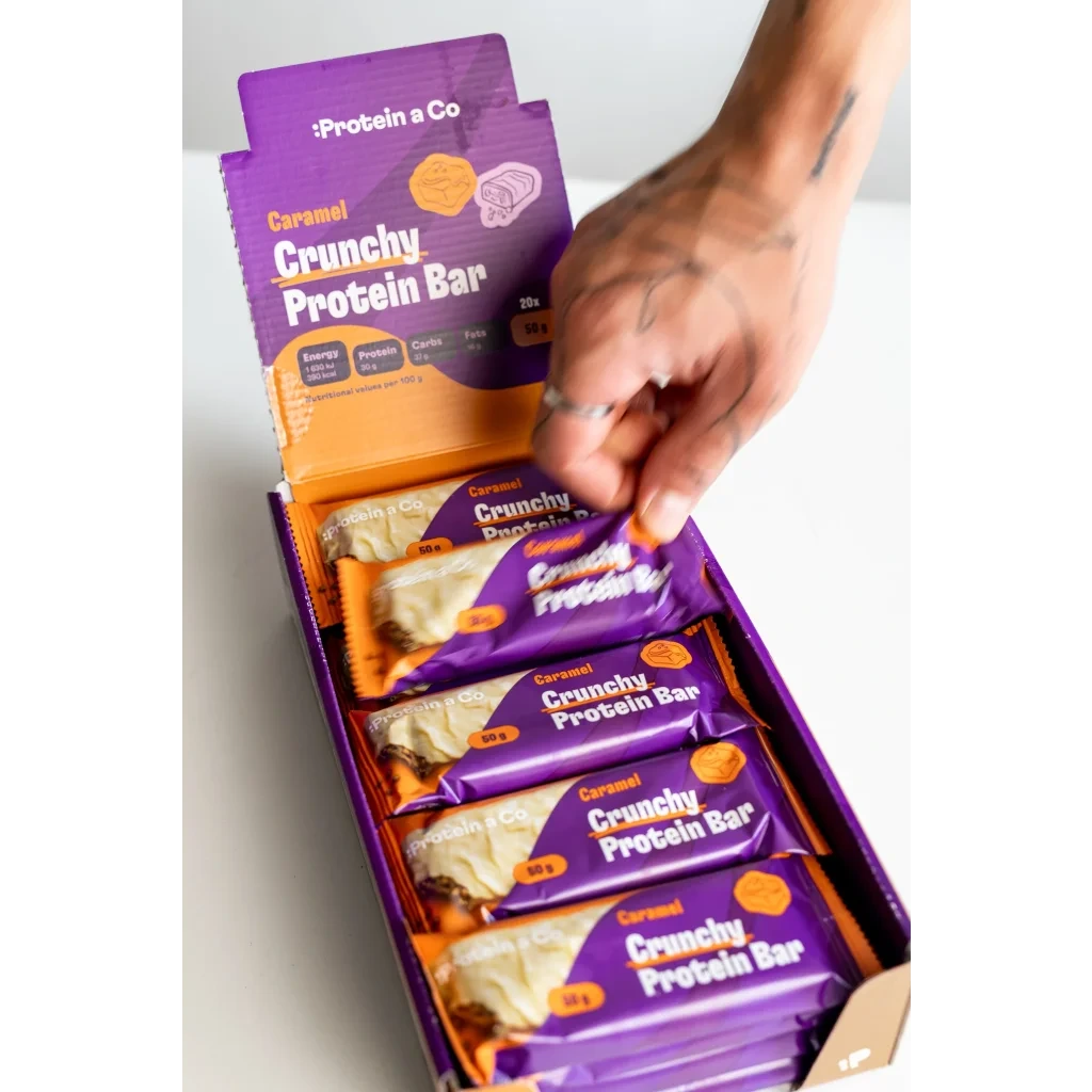 Ruka bere Crunchy proteinovou tyčinku karamel z boxu